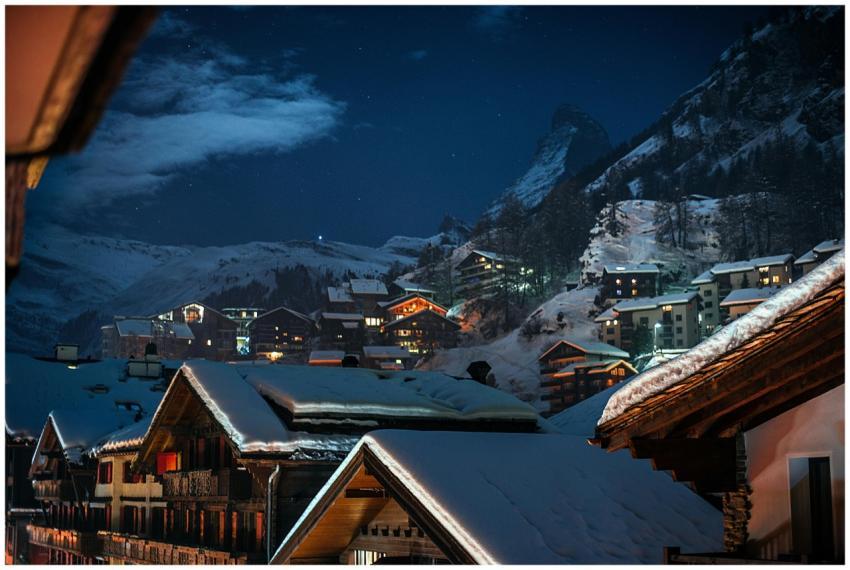 Scenic alpine village covered in snow, illuminated