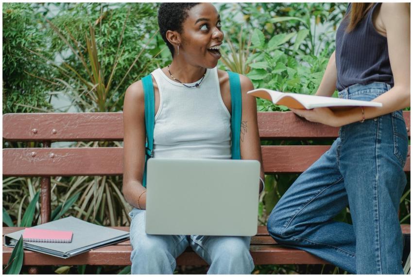 Multiracial female friends talking on bench in par