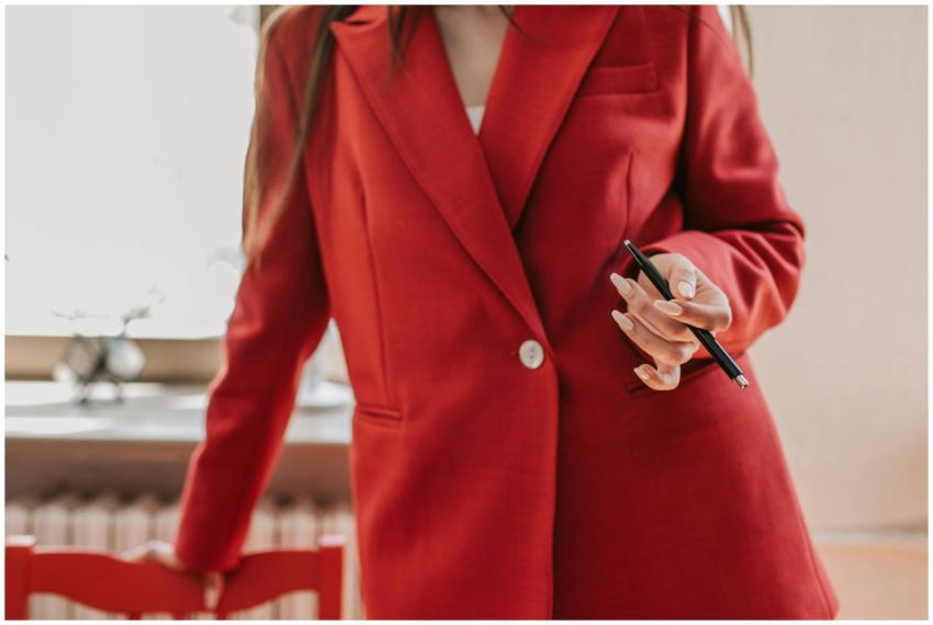Confident woman in red blazer holding a pen, ready