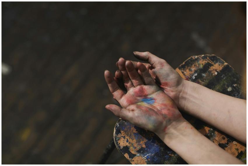 Close-up of hands covered in colorful paint, showc