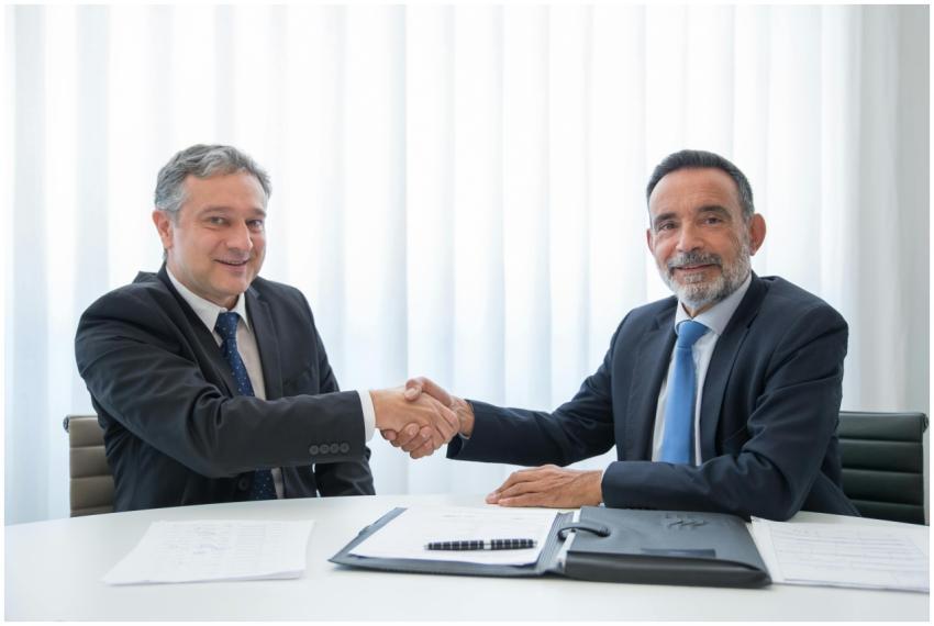 Two businessmen in suits shaking hands at an offic