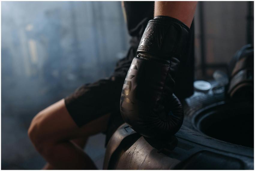 A boxer in black gloves resting their hand on a ti