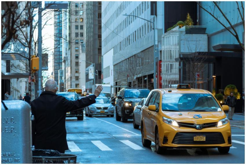 A man hailing a yellow taxi in bustling NYC street