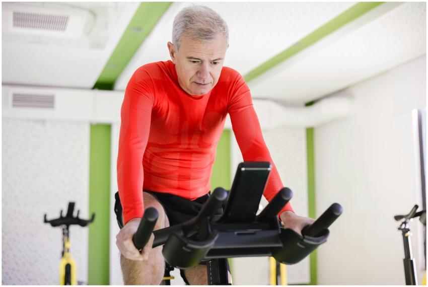 Senior man in red activewear exercising on station