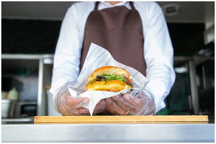 A chef in a food truck presents a gourmet burger w