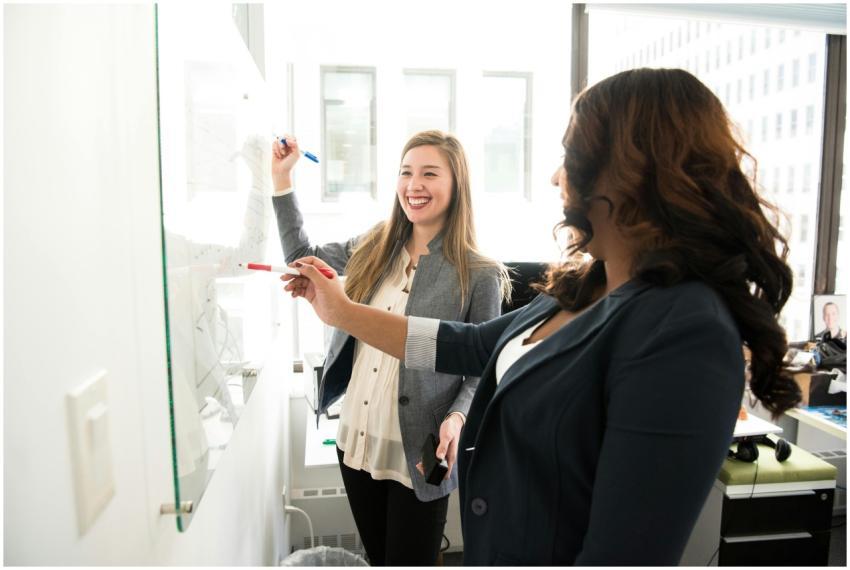 Two professional women discussing ideas on a white