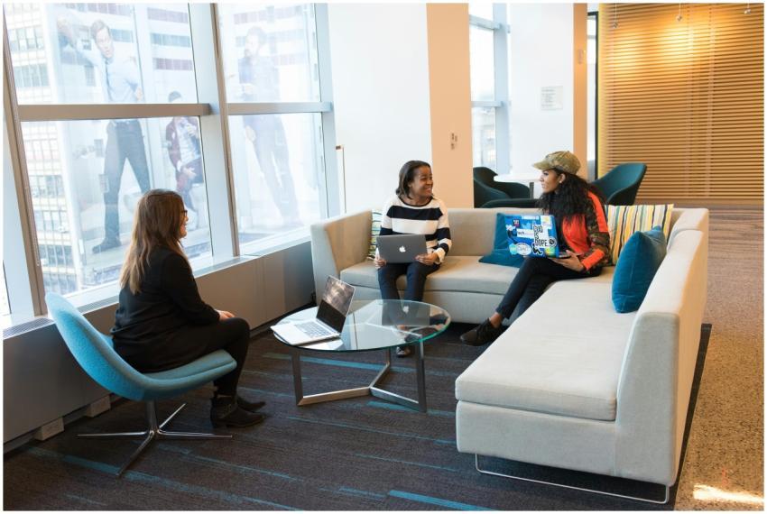 Three women engaged in a meeting with laptops in a