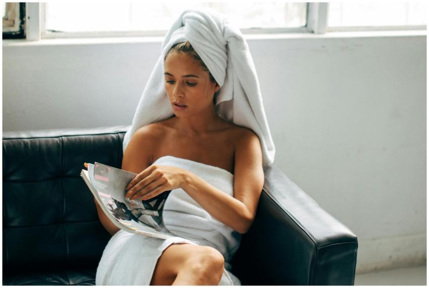 Woman wrapped in towel reading magazine, enjoying