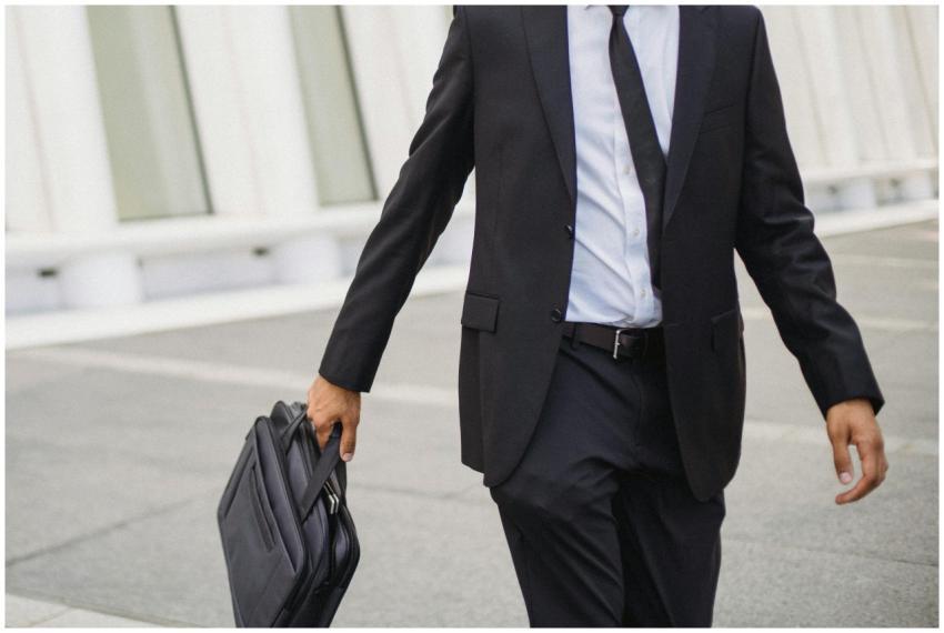 A businessman in a suit carrying a briefcase walks