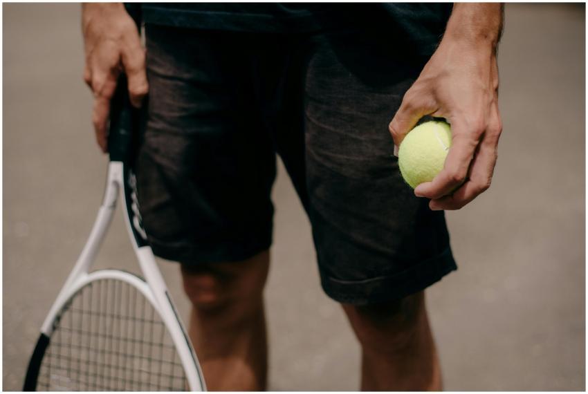 Close-up of a man holding a tennis racket and ball