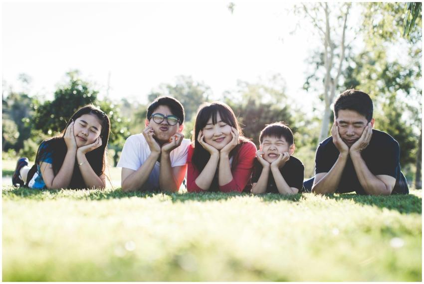 Asian family posing happily on the grass in a sunn