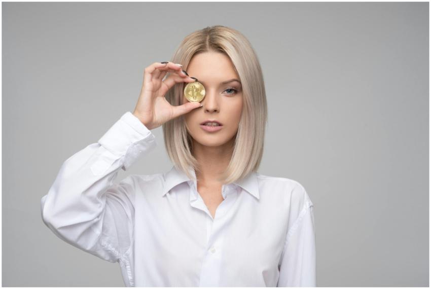 Blonde woman in white shirt holding a bitcoin in f