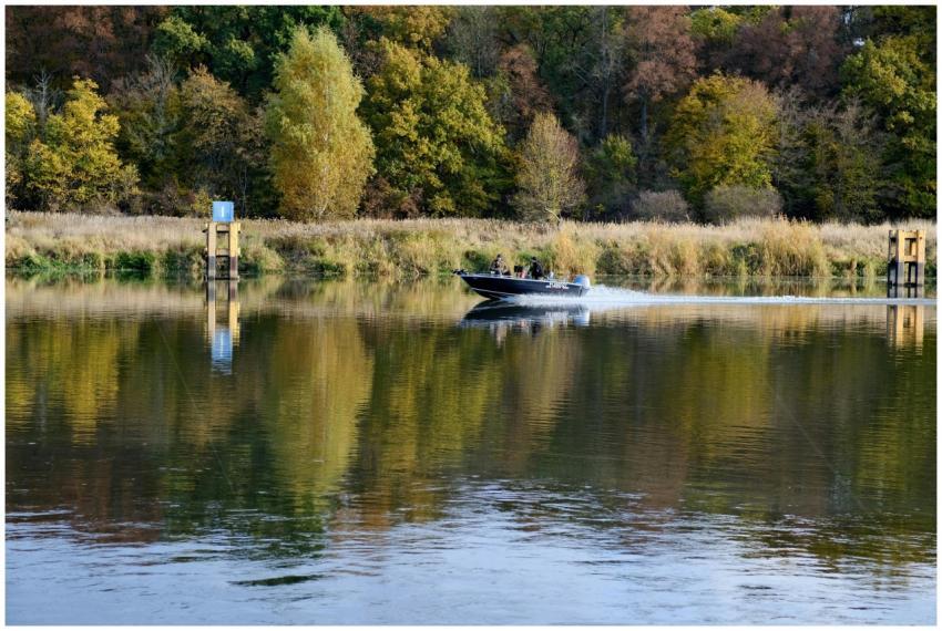 A speedboat glides across a reflective lake surrou