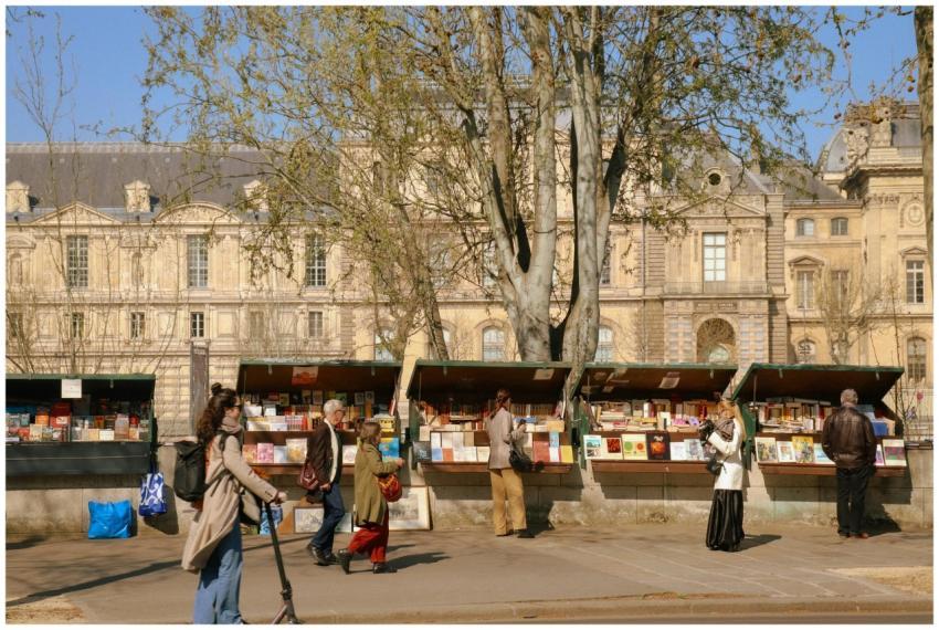 People browsing bookstalls by the Seine River in P