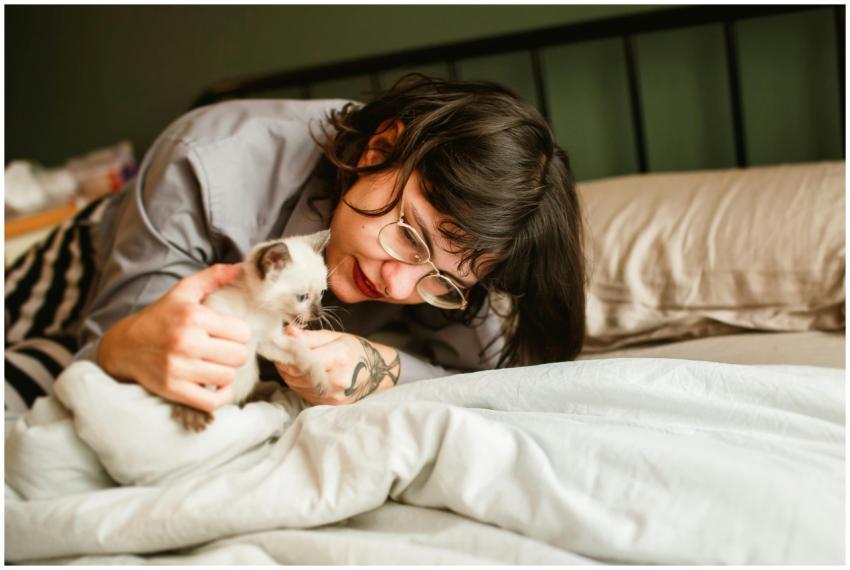 A woman lovingly playing with her Siamese kitten o
