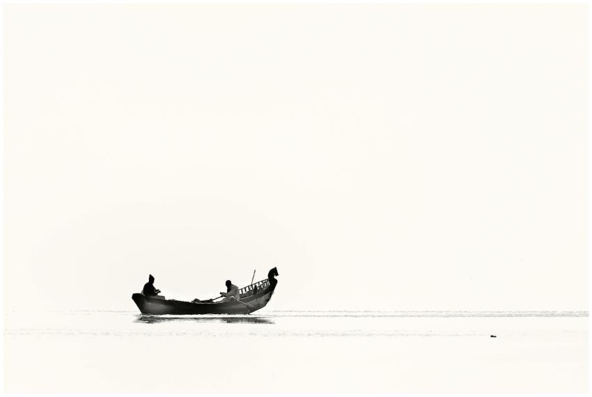 Silhouetted fishermen in a boat on a tranquil wate