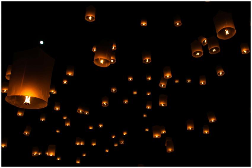Sky lanterns float against a dark night sky during
