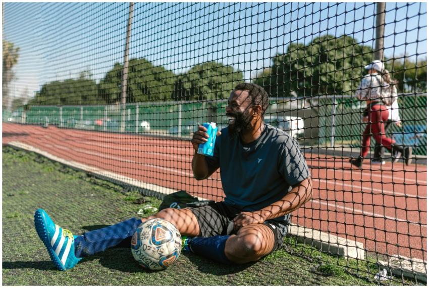 Smiling soccer player taking a break with a drink