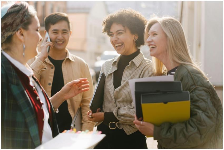 Group of adults laughing and conversing outdoors,