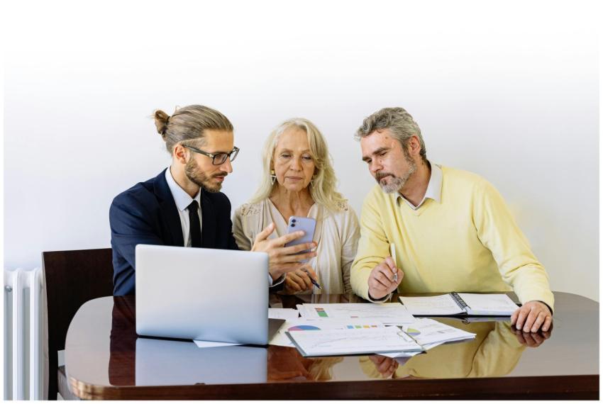 Three individuals collaborating on financial docum