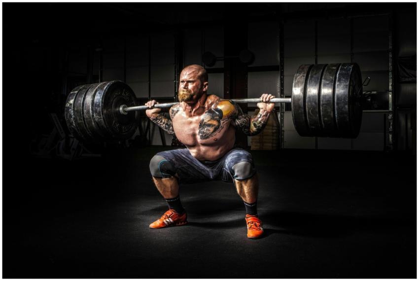 Muscular man lifting heavy weights during an inten