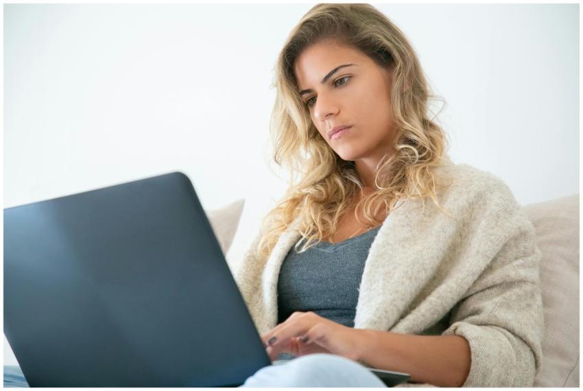Blonde woman working on a laptop, deeply focused i