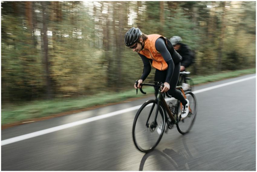Two cyclists in activewear racing on an open road