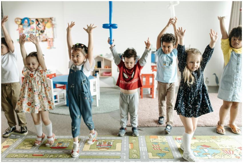 A diverse group of children raising hands while ha