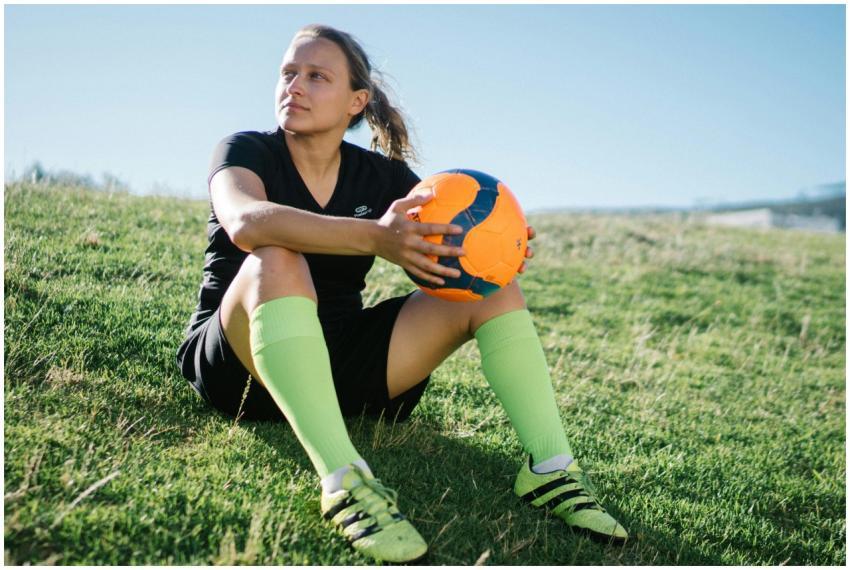 Young female soccer player relaxing with an orange