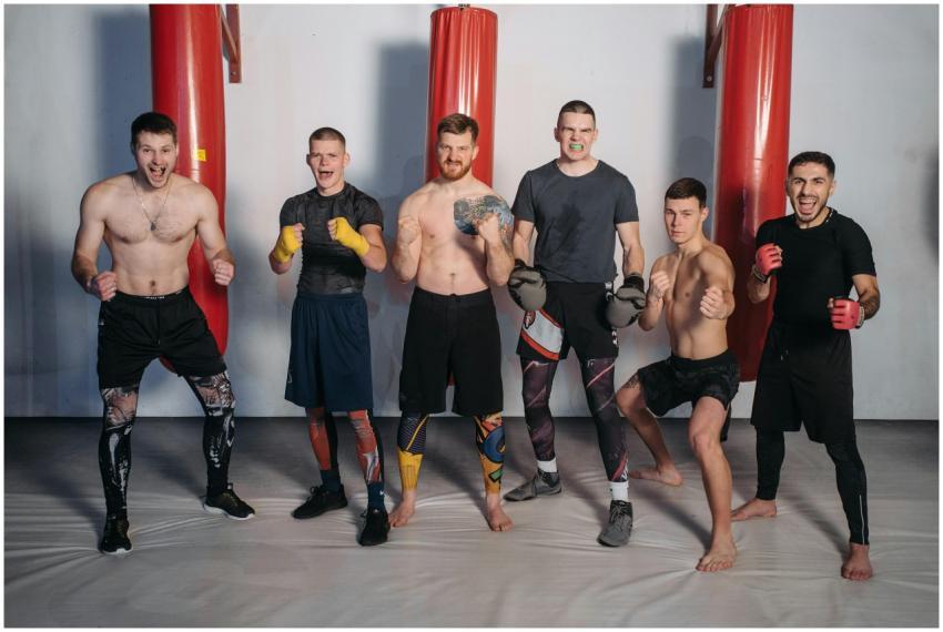 Six male fighters posing confidently in a gym, rea