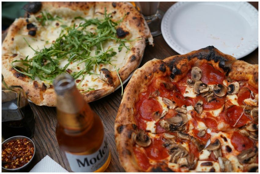 Two gourmet pizzas with fresh toppings on a rustic