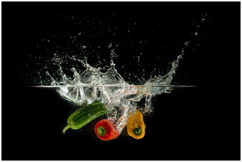 Colorful bell peppers splashing in clear water aga