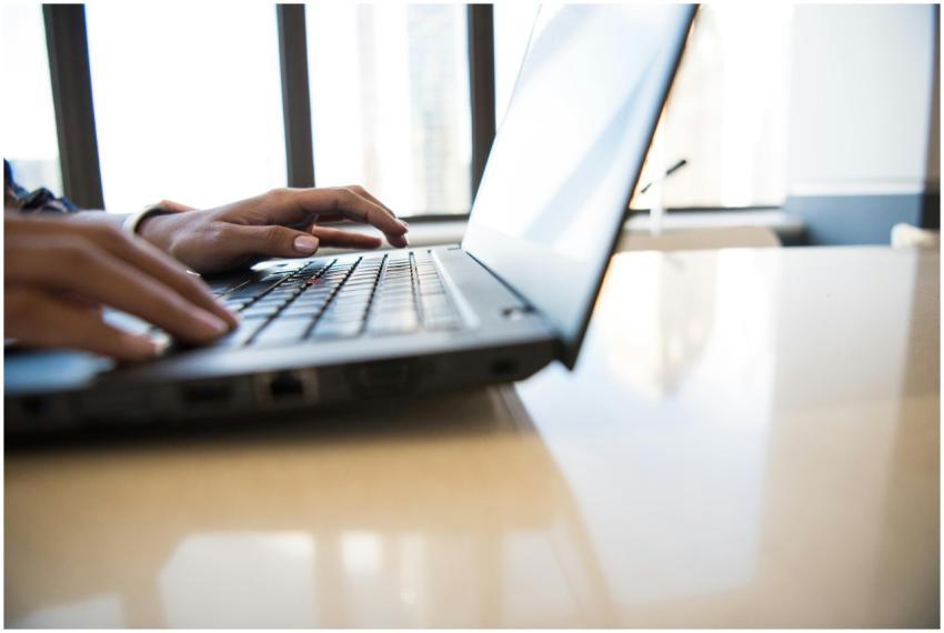 Close-up of woman's hands typing on a laptop in a
