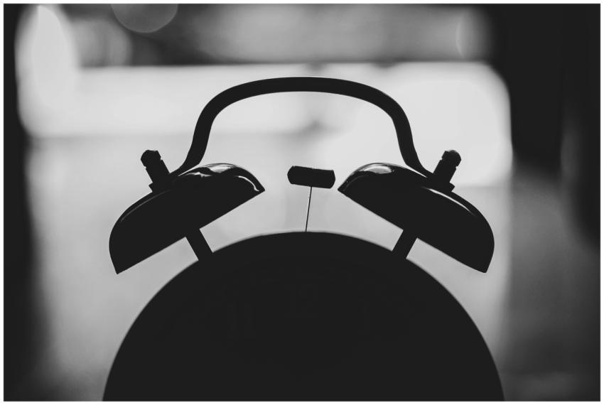 Artistic silhouette of a vintage alarm clock in bl