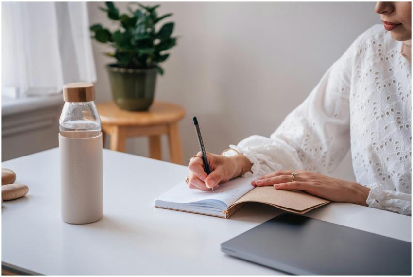 Adult writing in a notebook at a desk, stylish pen