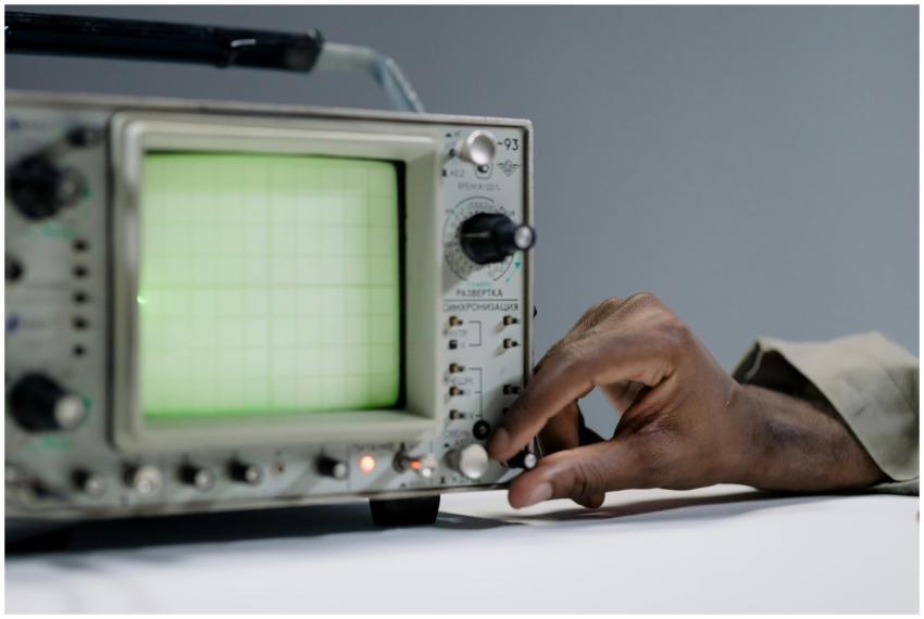 A person adjusts settings on a vintage oscilloscop