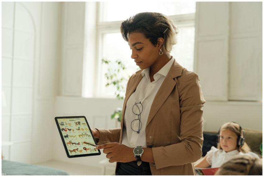 A teacher using a tablet in a bright classroom to