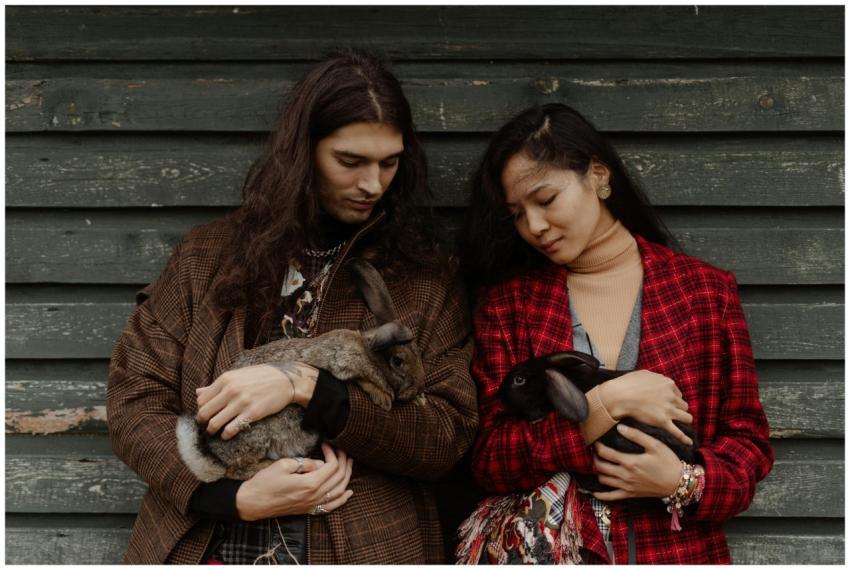 Man and woman stylishly dressed holding rabbits in