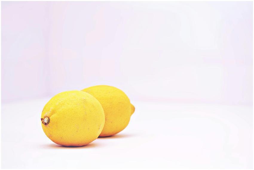 Two vibrant lemons placed against a minimalistic w
