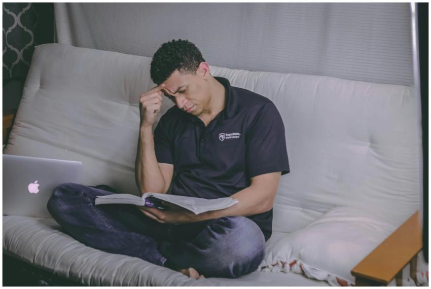 A student relaxing on a sofa, studying with a book