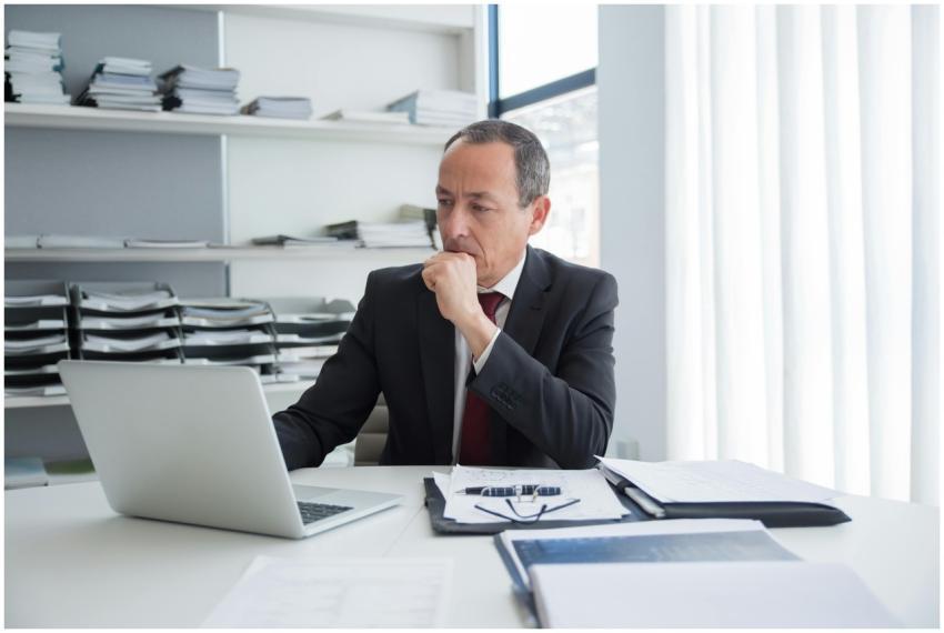 Mature business executive thoughtful at desk with