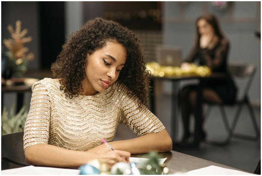 Young woman writing in a festive indoor office wit