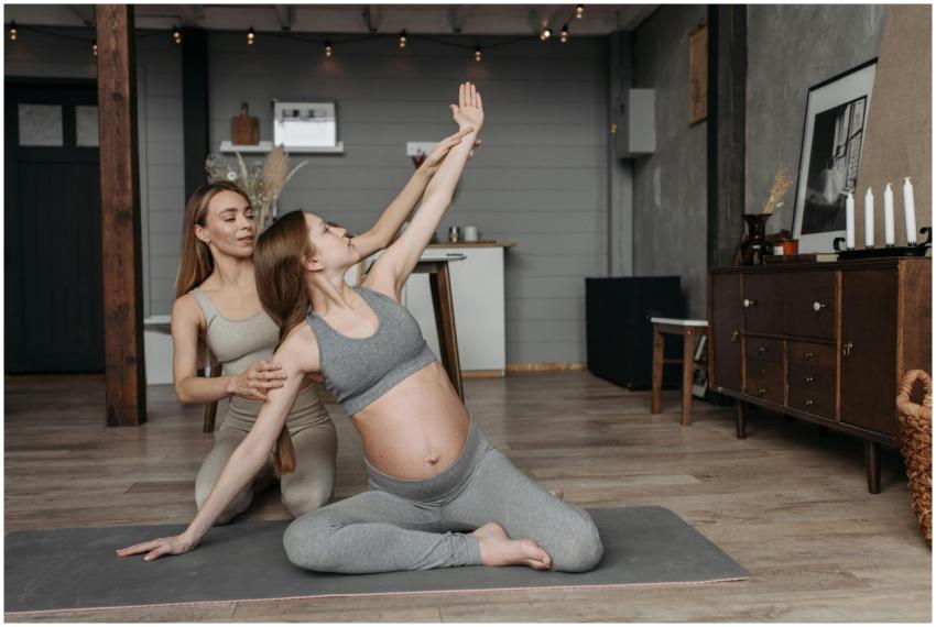 Pregnant woman on yoga mat with instructor, focusi