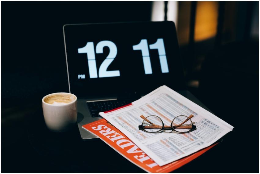 A desk setup featuring a laptop, coffee cup, paper
