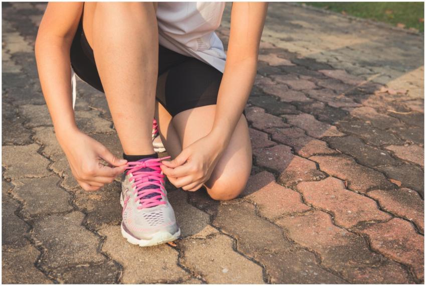 Adult woman tying pink laces on running shoes outd