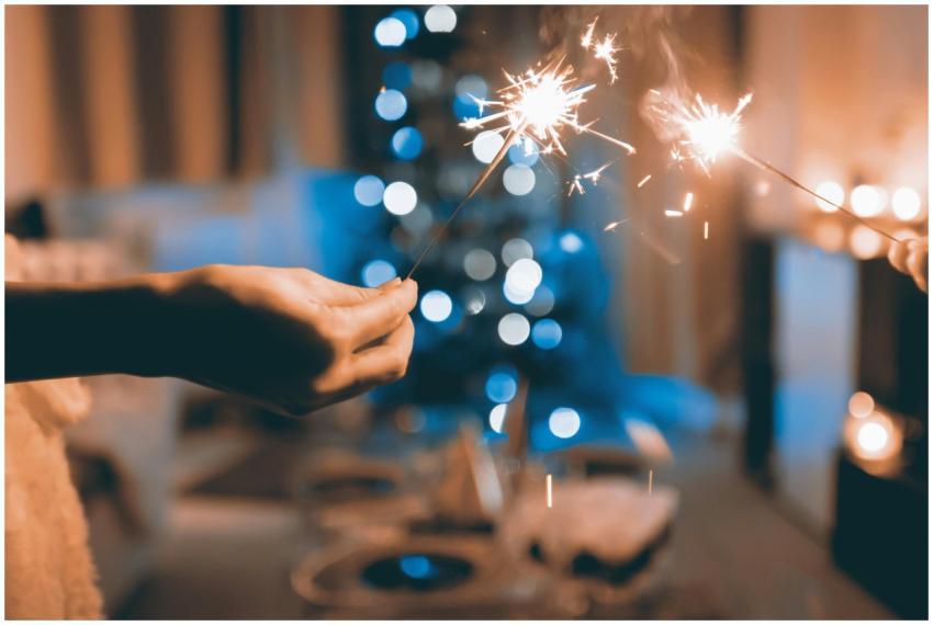 Hands holding sparklers in a festive indoor settin