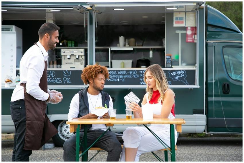 Cheerful owner of food truck standing near table w