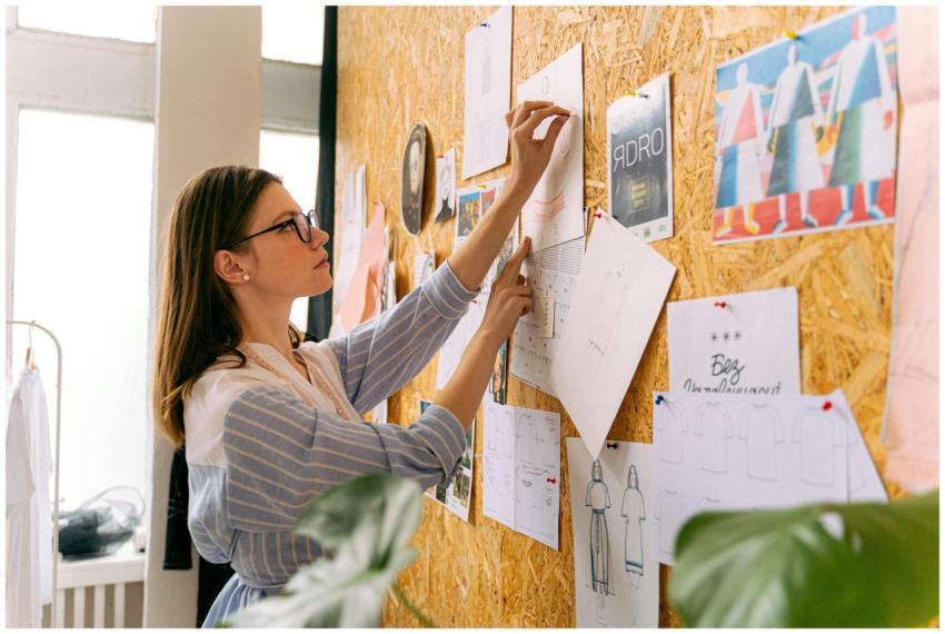A woman fashion designer pinning sketches in a stu