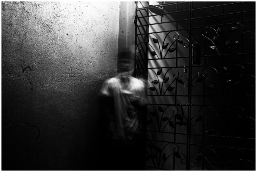 Grayscale photo of a blurred figure in an eerie in