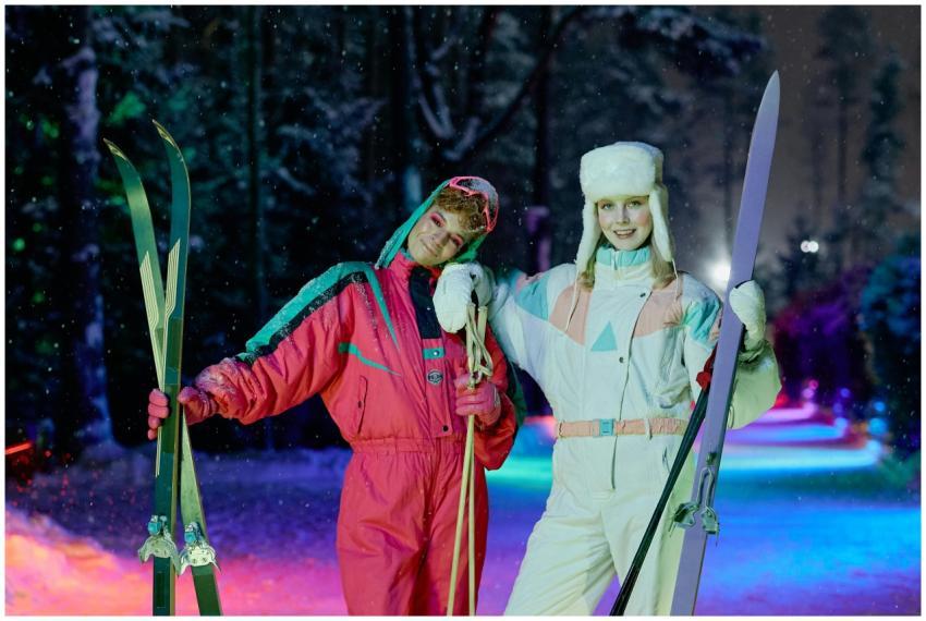 Two women in colorful ski outfits enjoying a winte